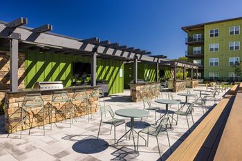 A patio with tables and chairs is covered by a roof.